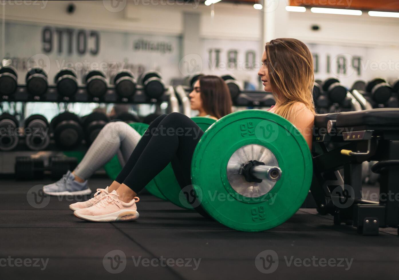 Two women sitting on a bench in a gym photo