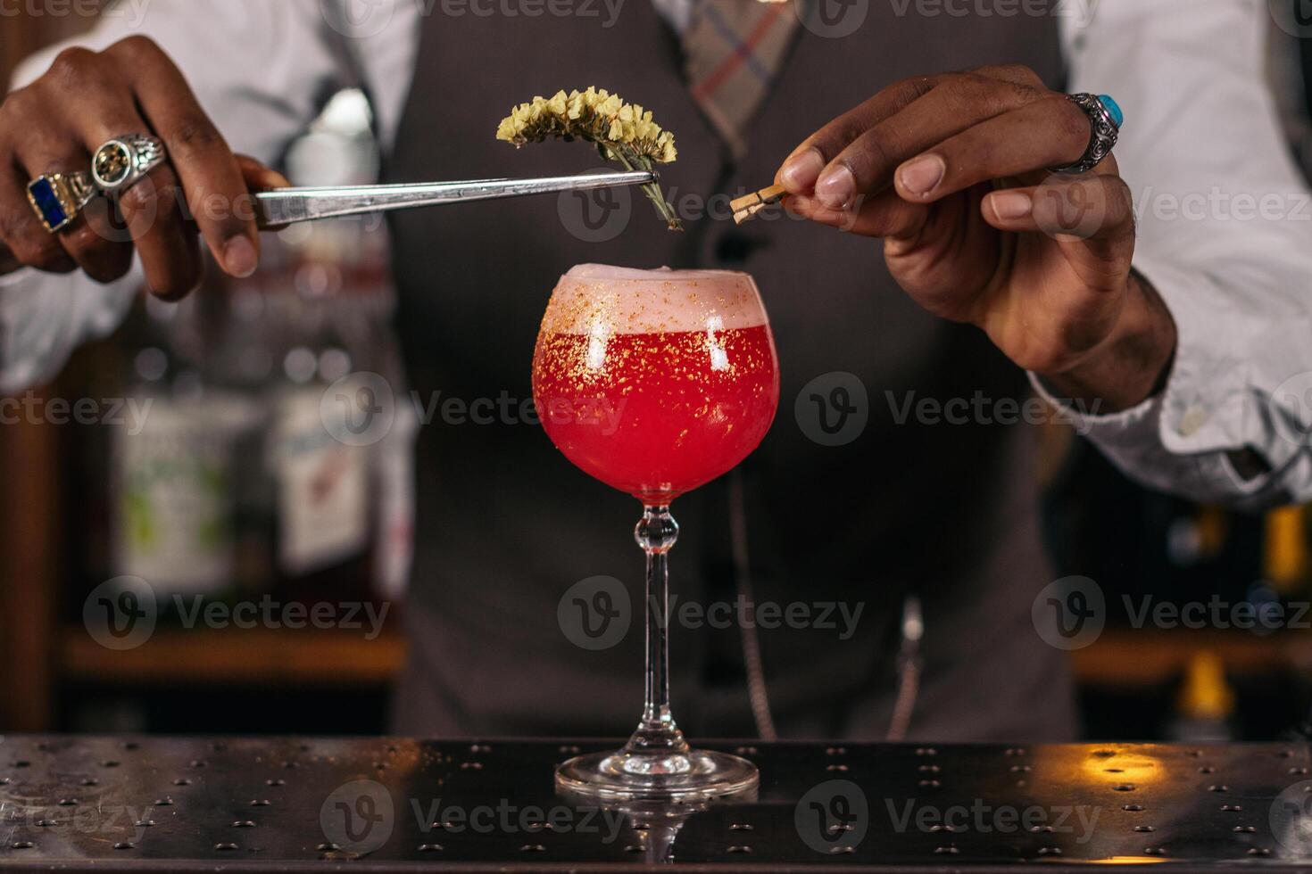 A bartender is preparing a cocktail by adding decoration to the cocktail photo