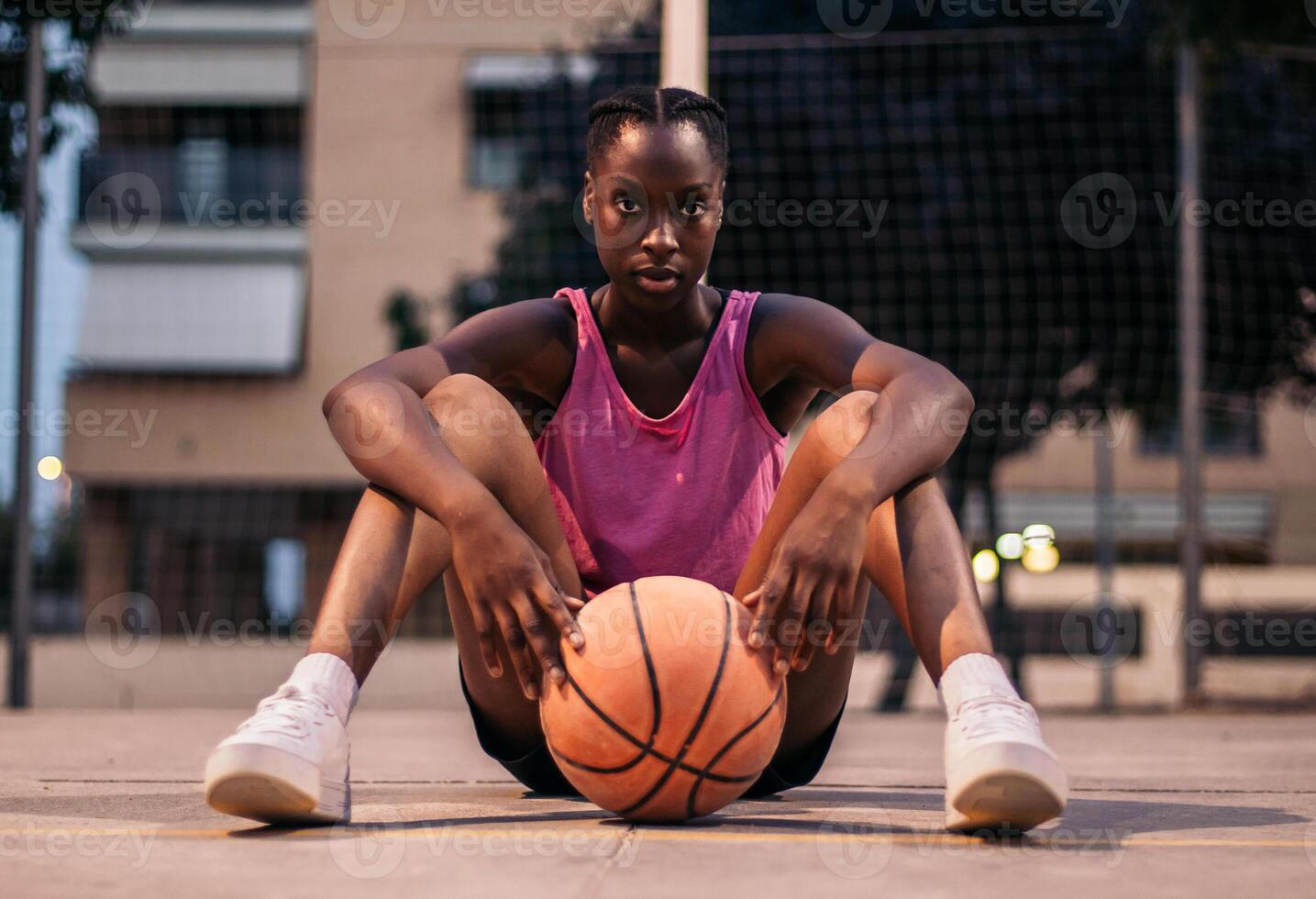 A young woman sitting on the ground with a basketball photo