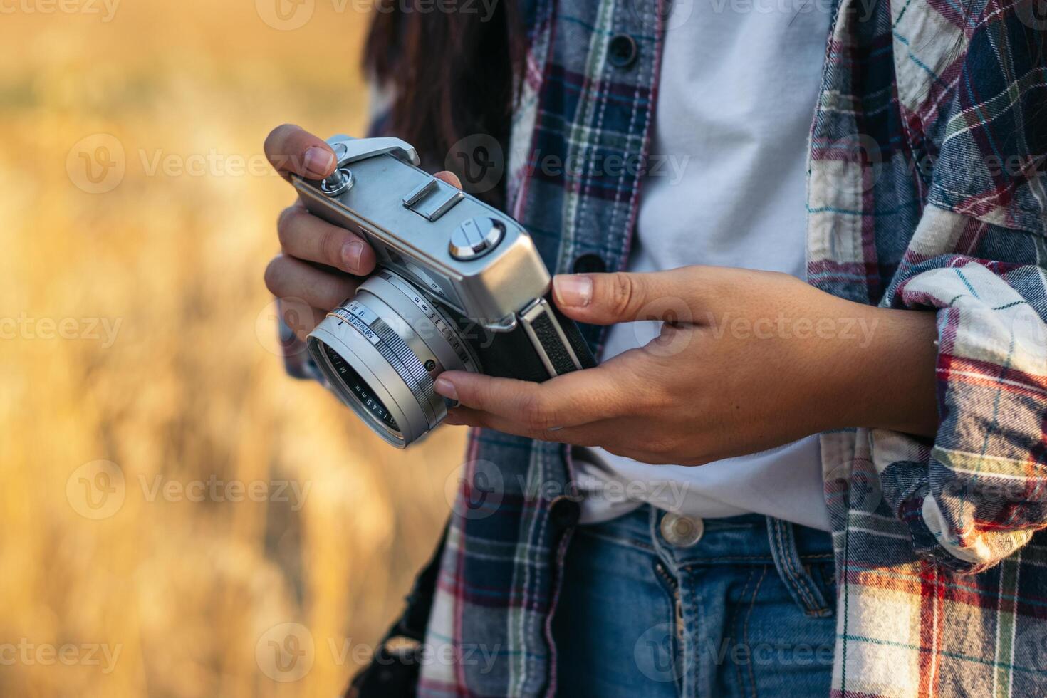A person holding a camera in front of a field photo