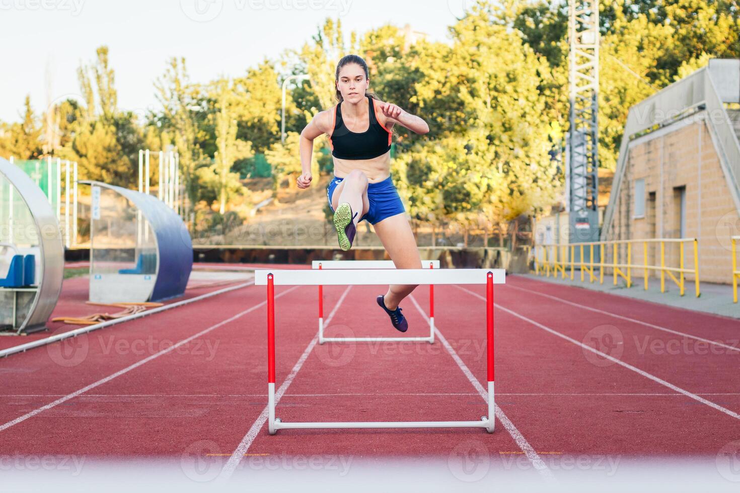 A woman is jumping over a hurdle on a track photo