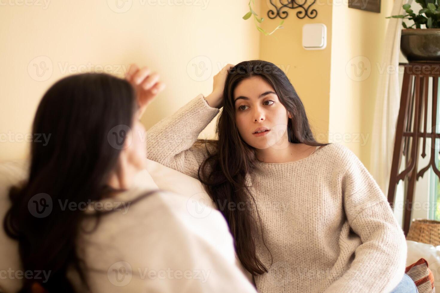 Two women sitting on a couch talking to each other photo