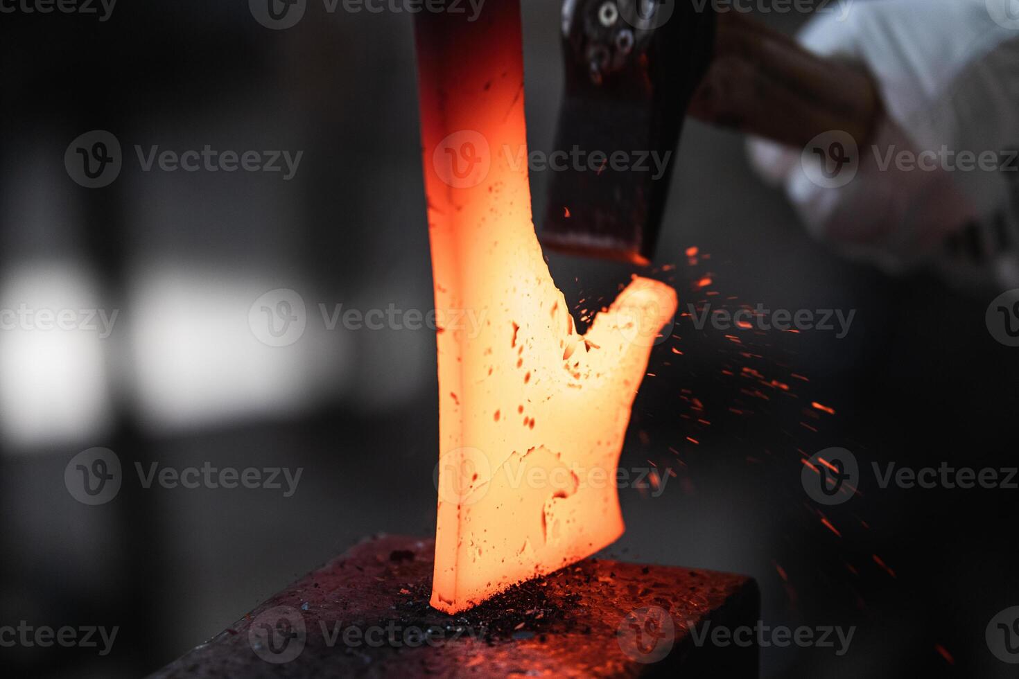 A person is using a hammer to make a piece of metal. photo