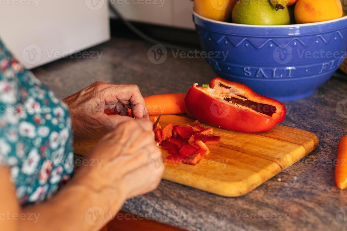 An older woman cutting up a red pepper photo