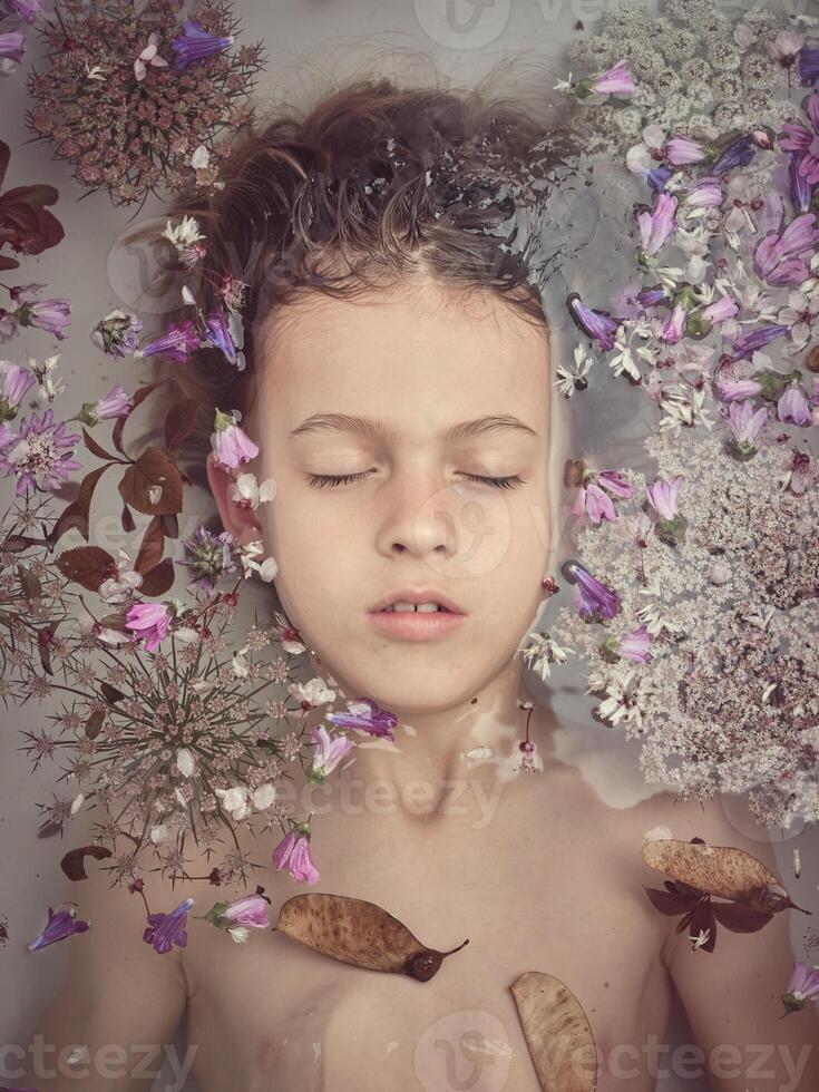 A young girl is floating in a bathtub with flowers photo