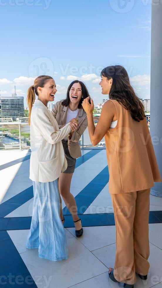 Three women in business attire talking and laughing photo