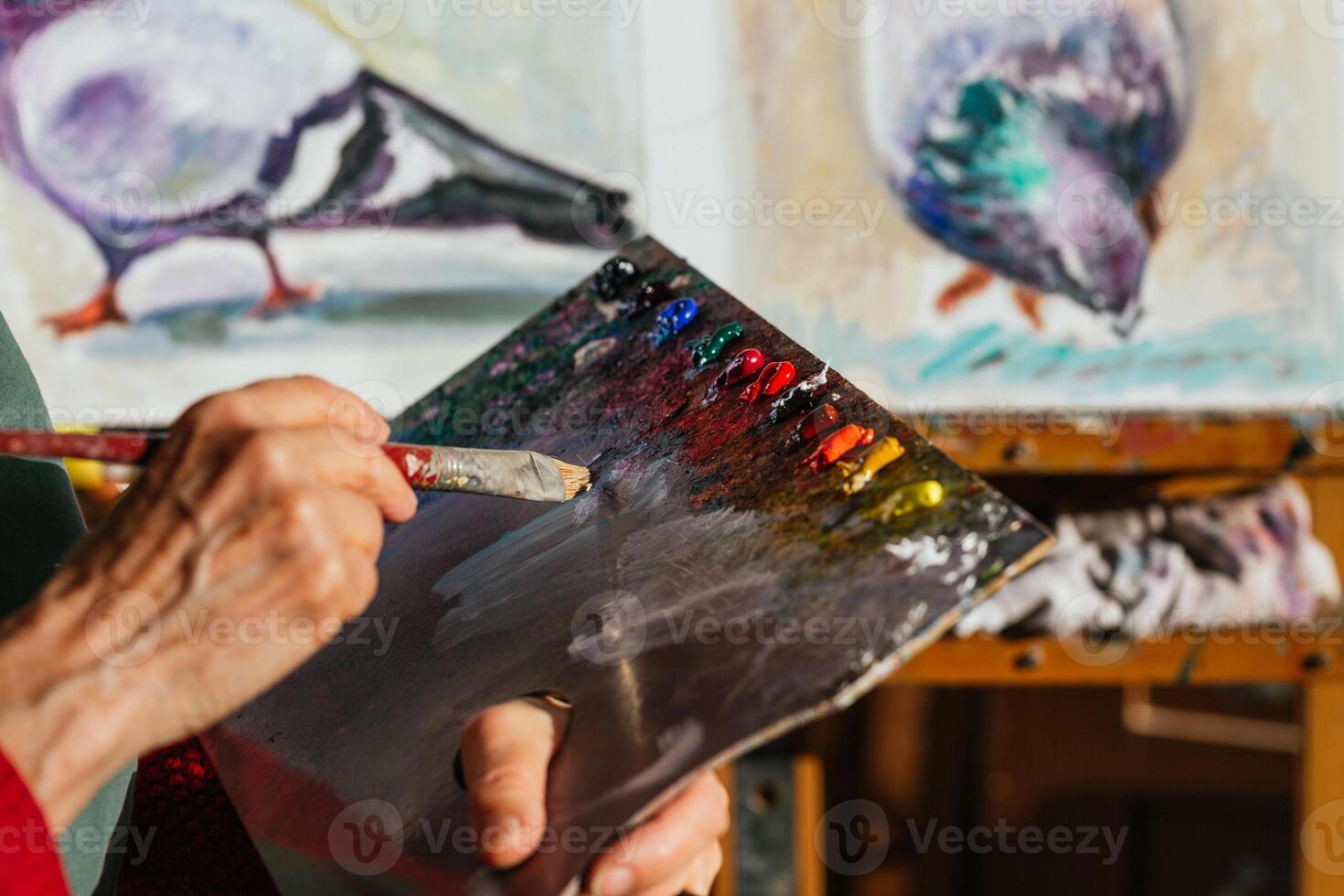 A woman holding a paintbrush and painting a bird photo