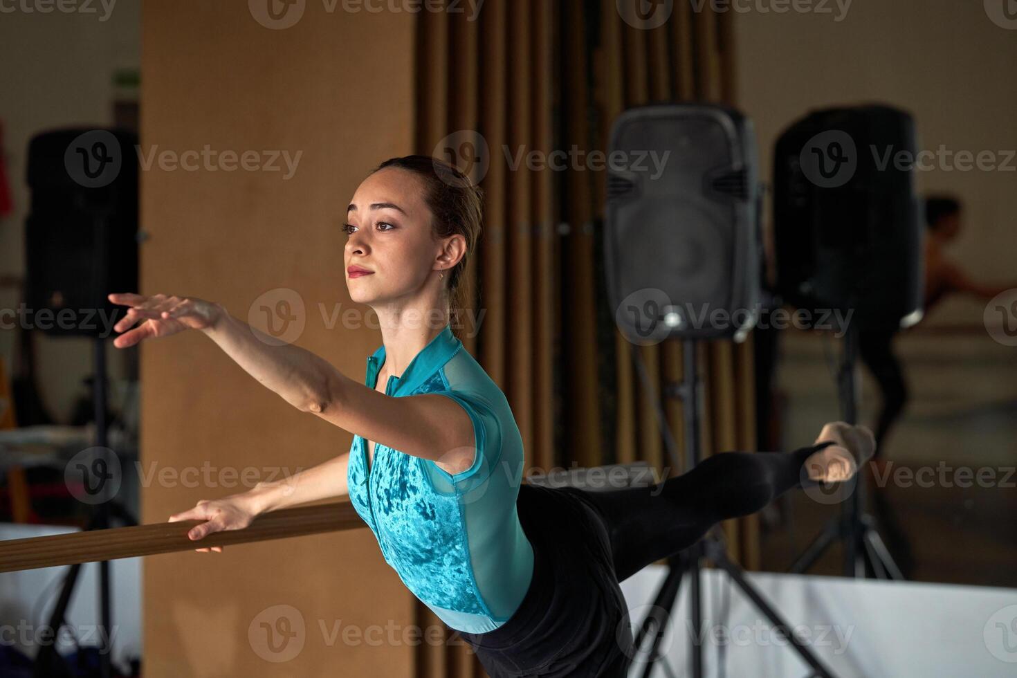 A woman in a blue shirt is doing a ballet pose photo