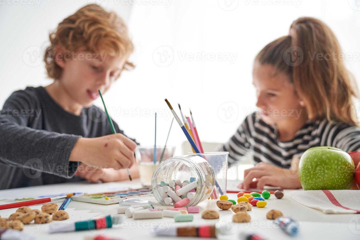 Two children are drawing on a table with crayons photo