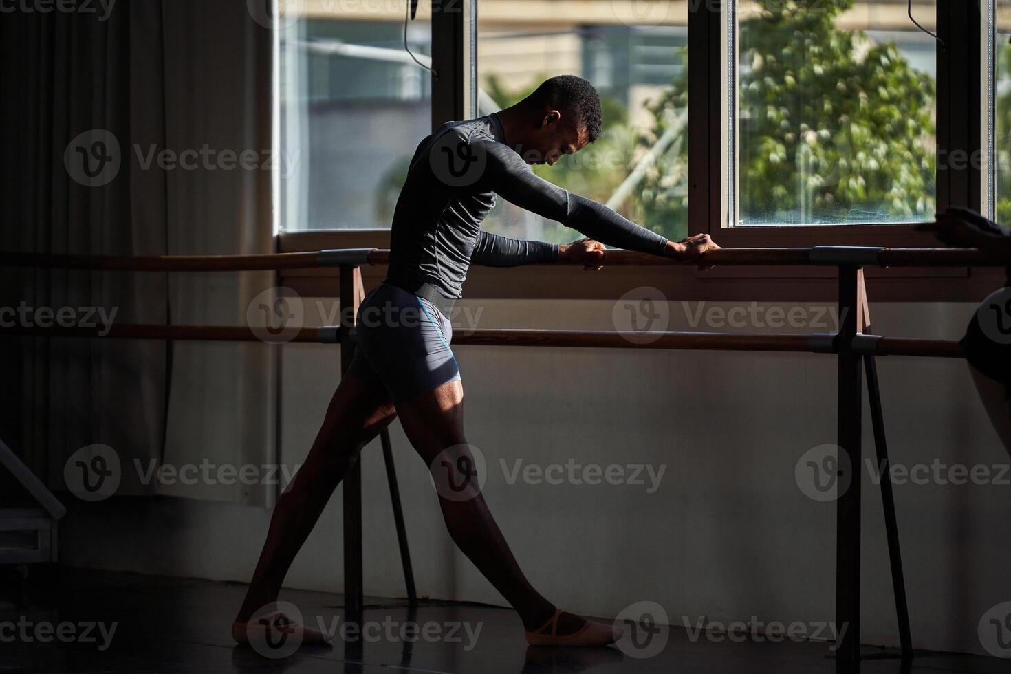 A young man in a ballet class is leaning against the rail photo