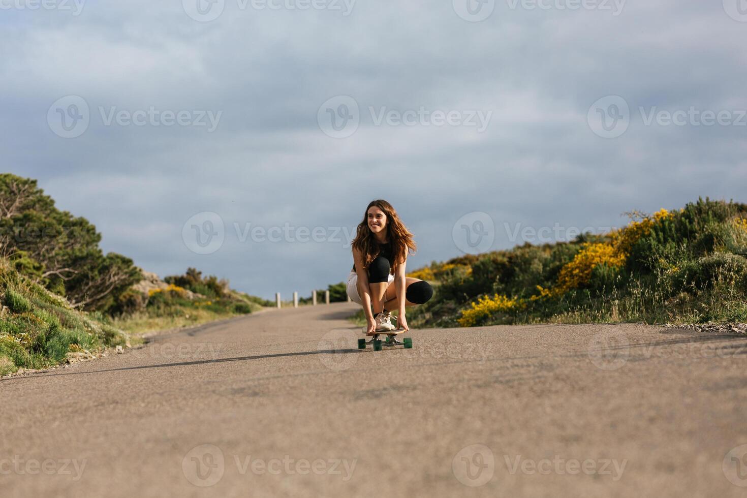 A woman riding a skateboard down a road photo