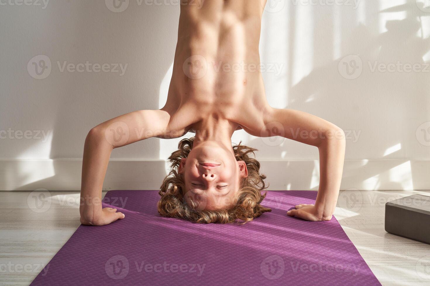 A young boy doing a handstand on a yoga mat photo