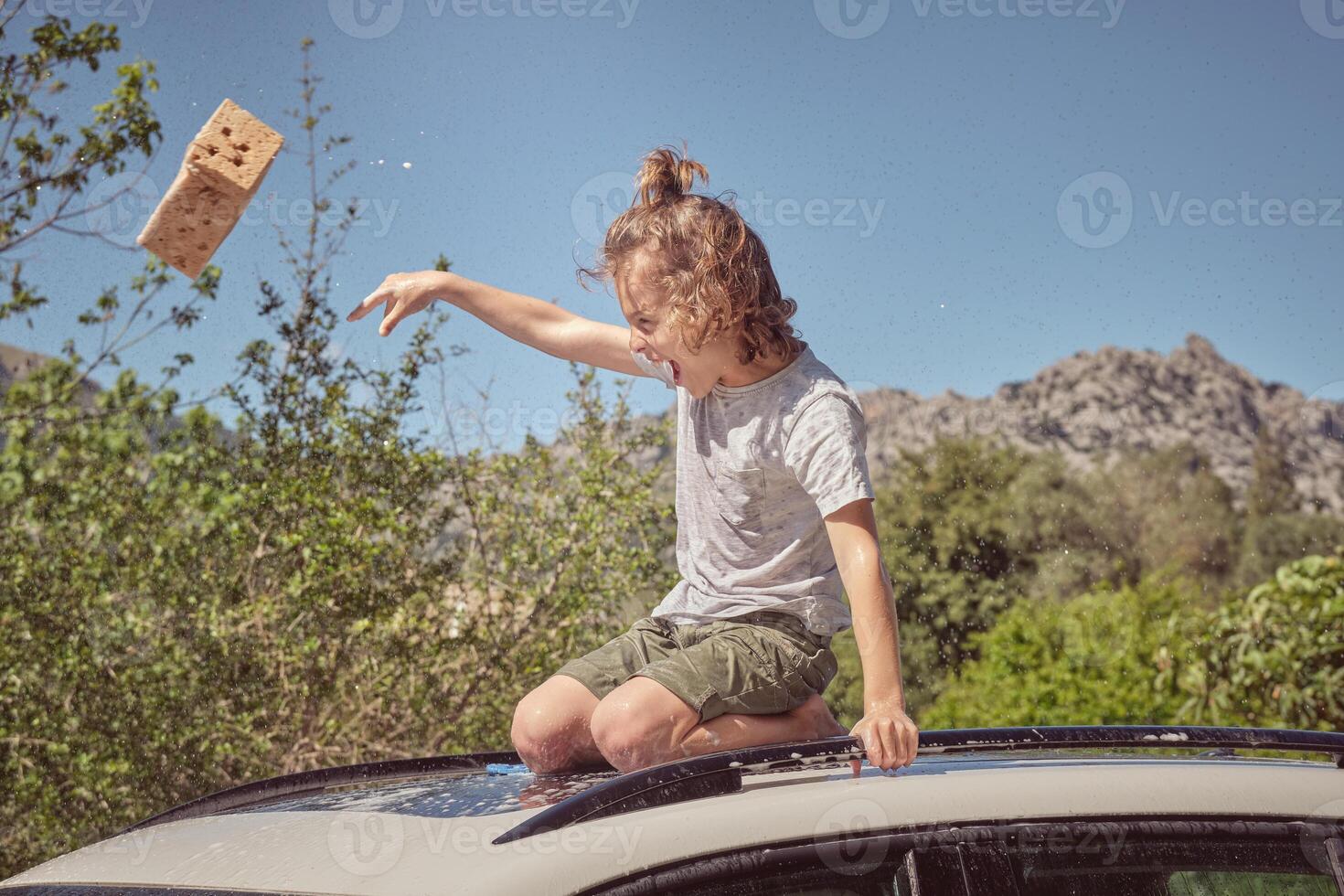 A young boy sitting on top of a car with a box photo