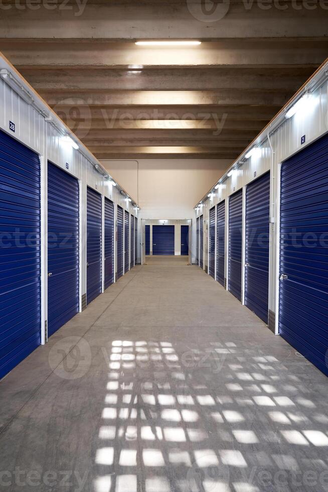 A long hallway with blue doors in a storage unit photo