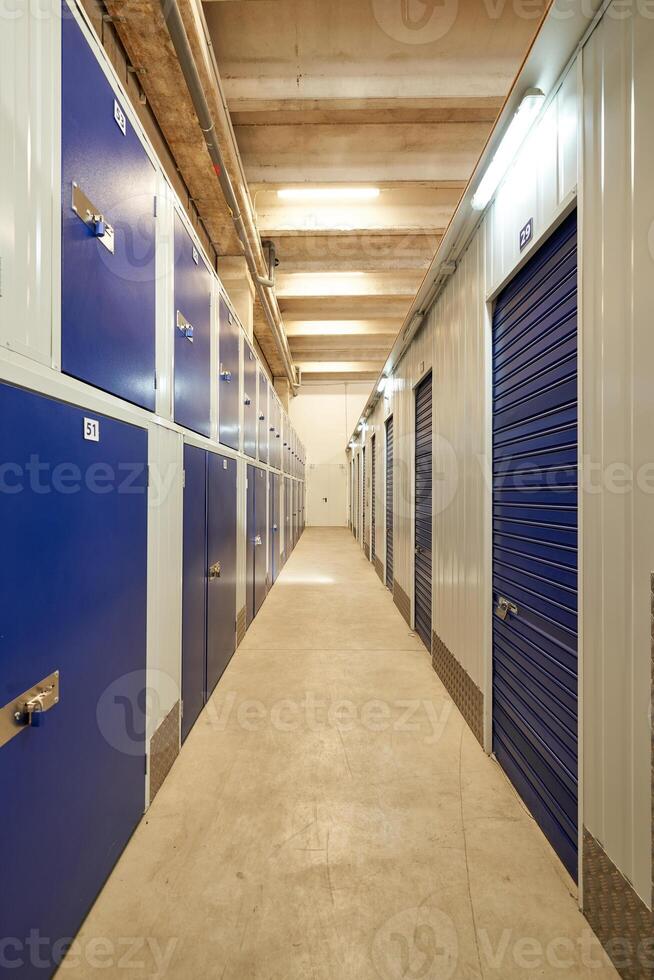 A long hallway with blue doors and storage units photo