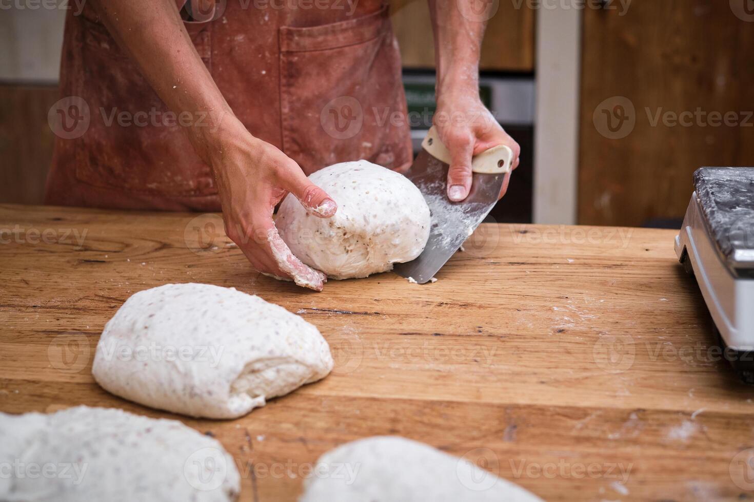 A person cutting dough on a wooden table photo