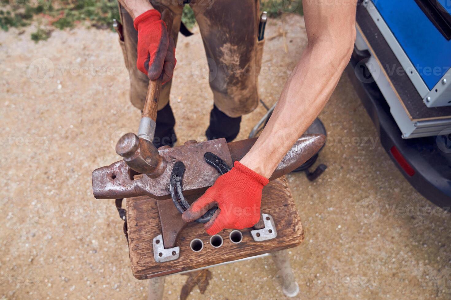 A man is using an anvil to hammer a piece of wood photo