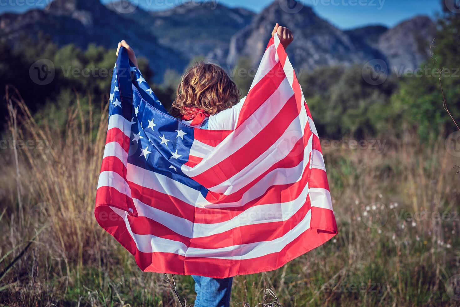 A woman holding an american flag in a field photo