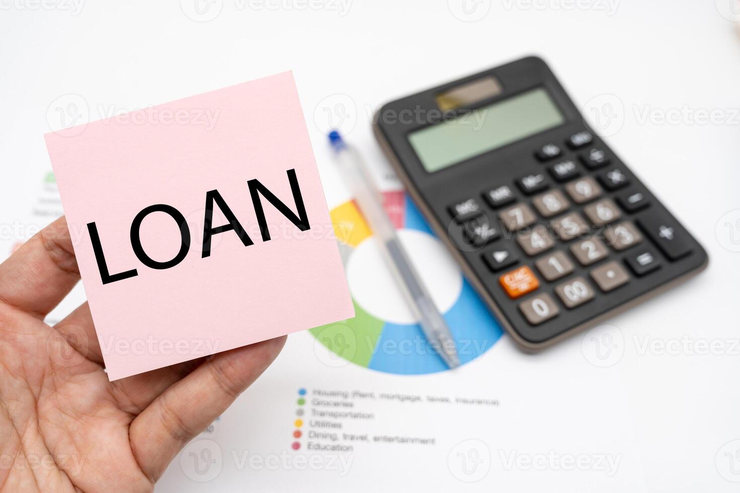 LOAN word on Pink sticky note with calculator and graph. Real estate market and finance concept. photo