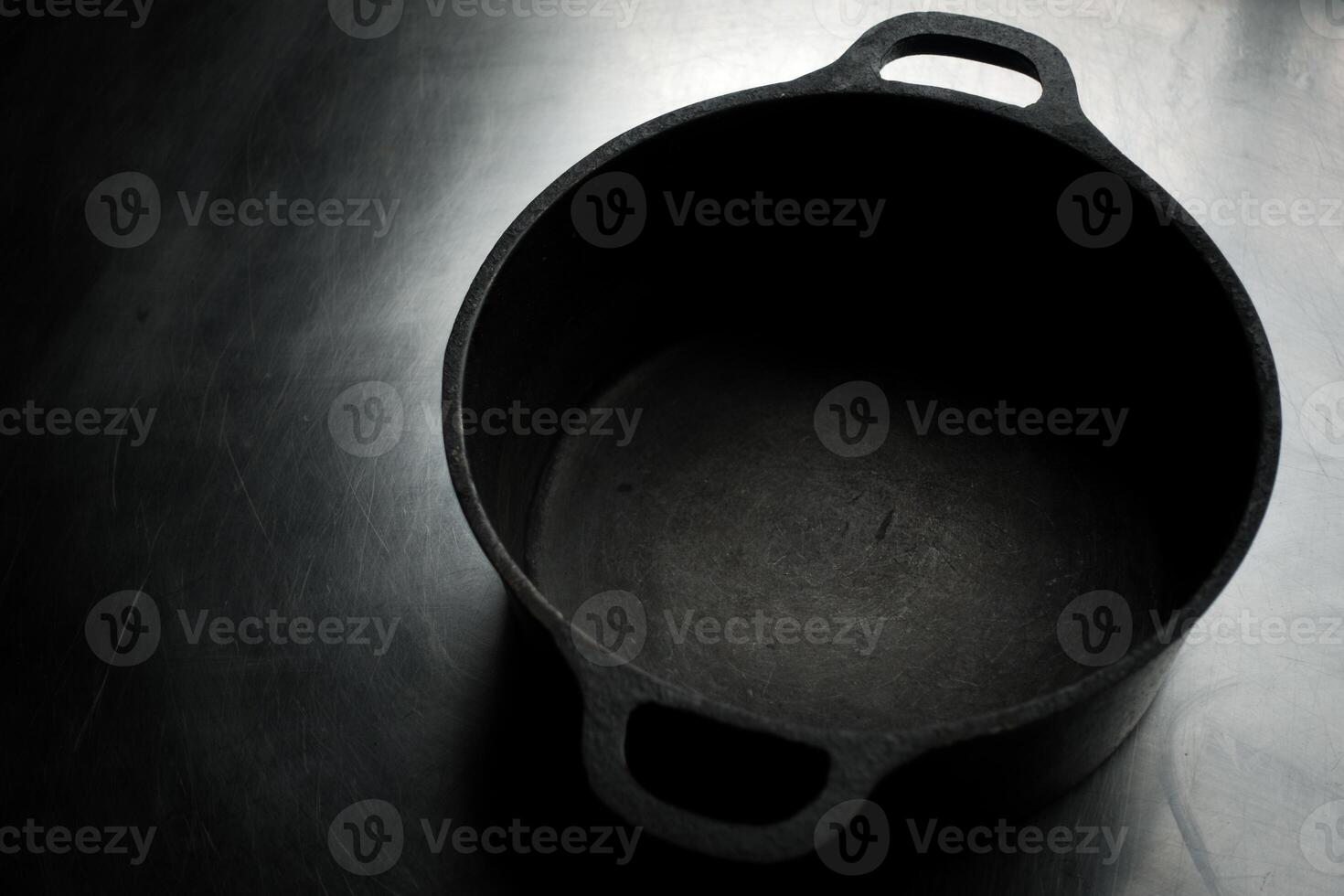 An empty cast iron pot on a metal surface photo