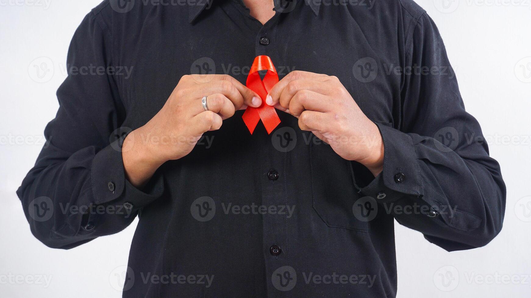Man holding red ribbon awareness in front of his chest isolated on white background photo