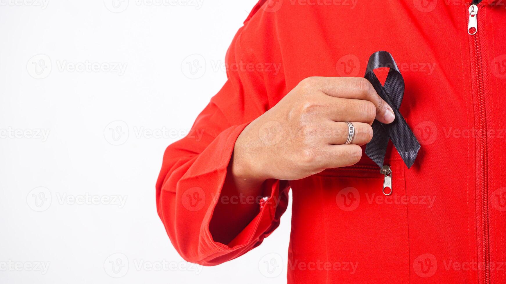 Man holding black ribbon in front of his chest as symbol of mourning and melanoma cancer awareness isolated on white background photo