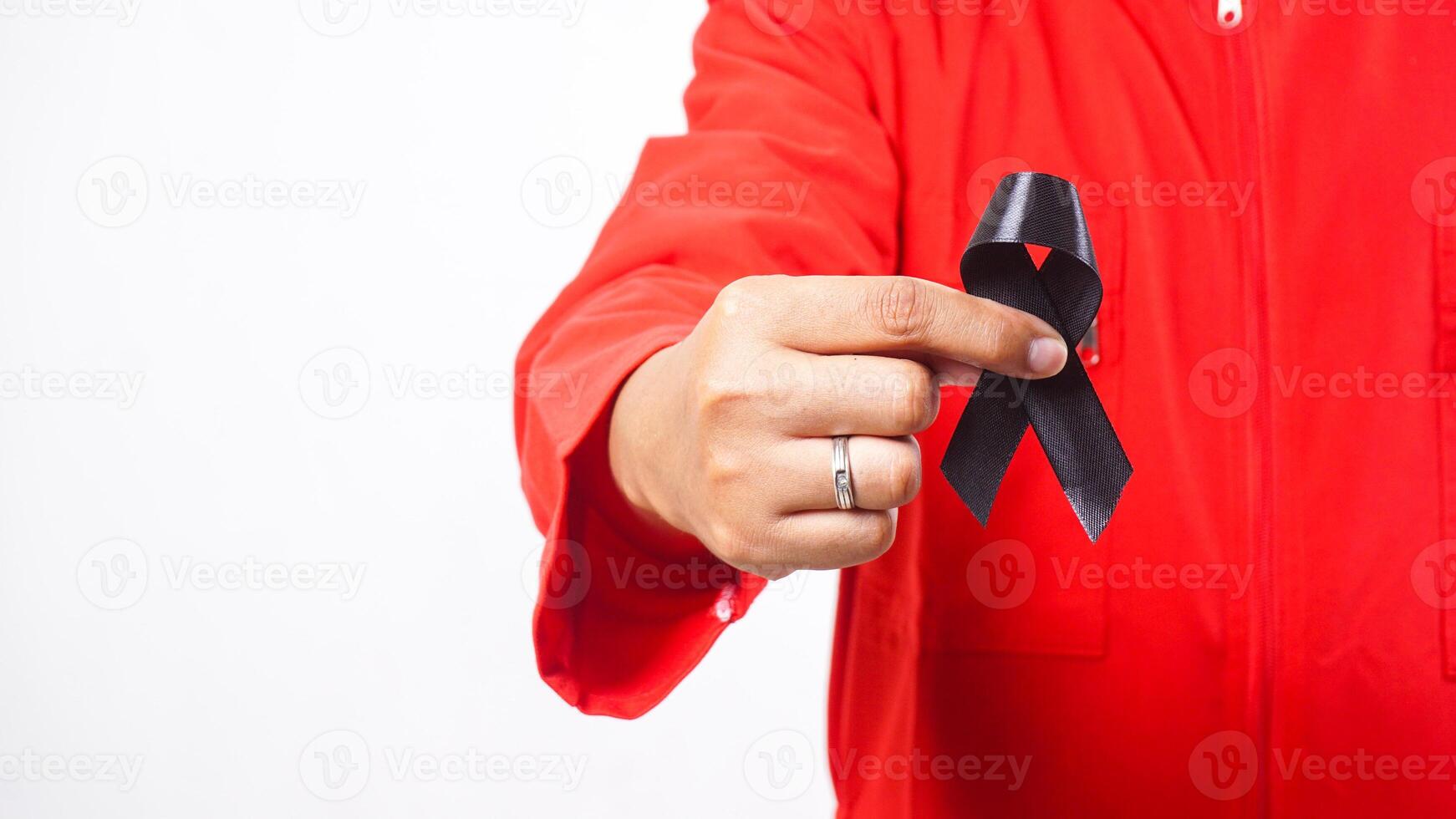 Close up of man holding black ribbon in front of his chest as symbol of mourning and melanoma cancer awareness isolated on white background photo
