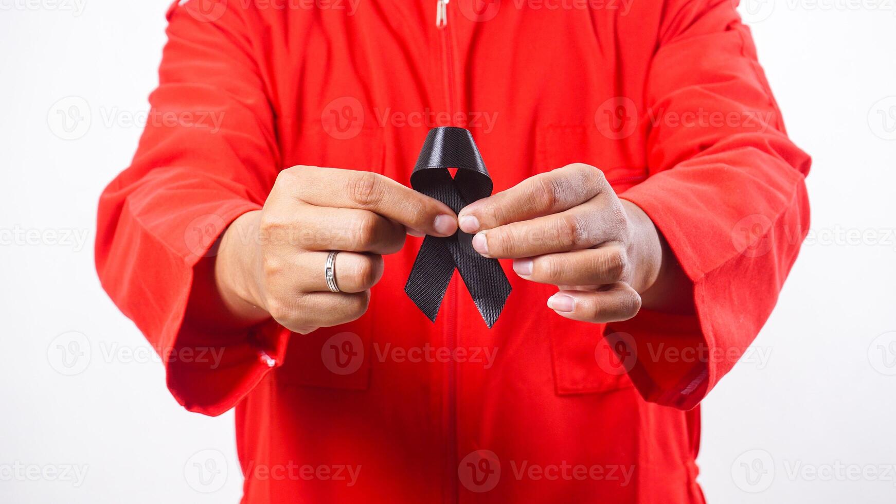 Close up of man hands holding black ribbon in front of his chest as symbol of mourning and melanoma cancer awareness isolated on white background photo