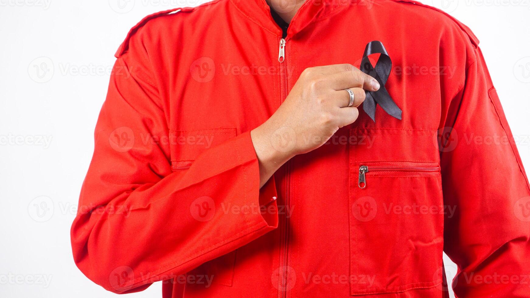 Hand of man holding black ribbon in front of his chest as symbol of mourning and melanoma cancer awareness isolated on white background photo