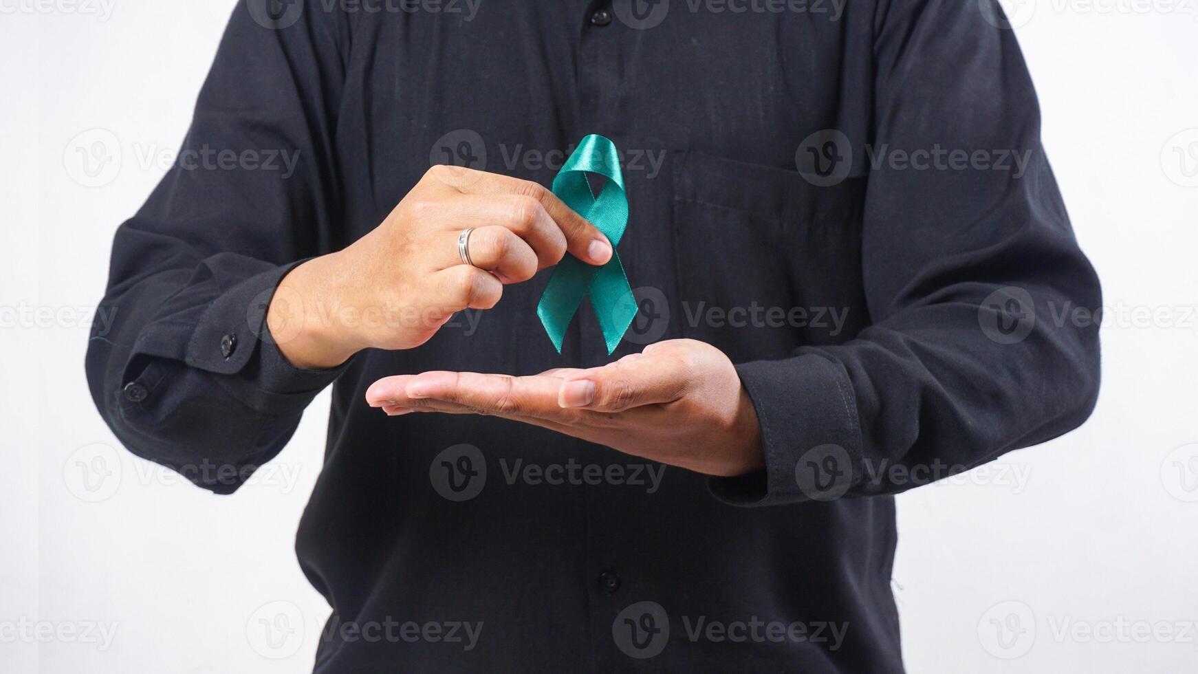 Man holding green awareness ribbon in front of his chest isolated on white background photo