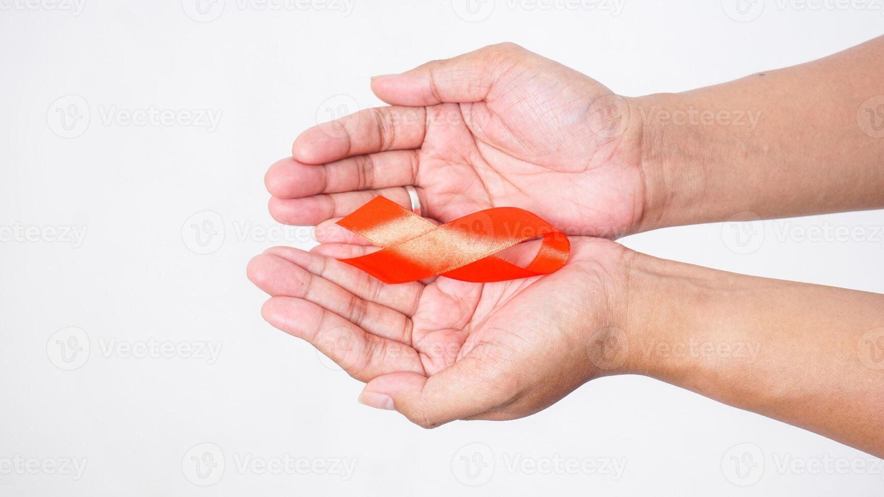 Hands showing red ribbon for awareness symbol on palm on white background photo