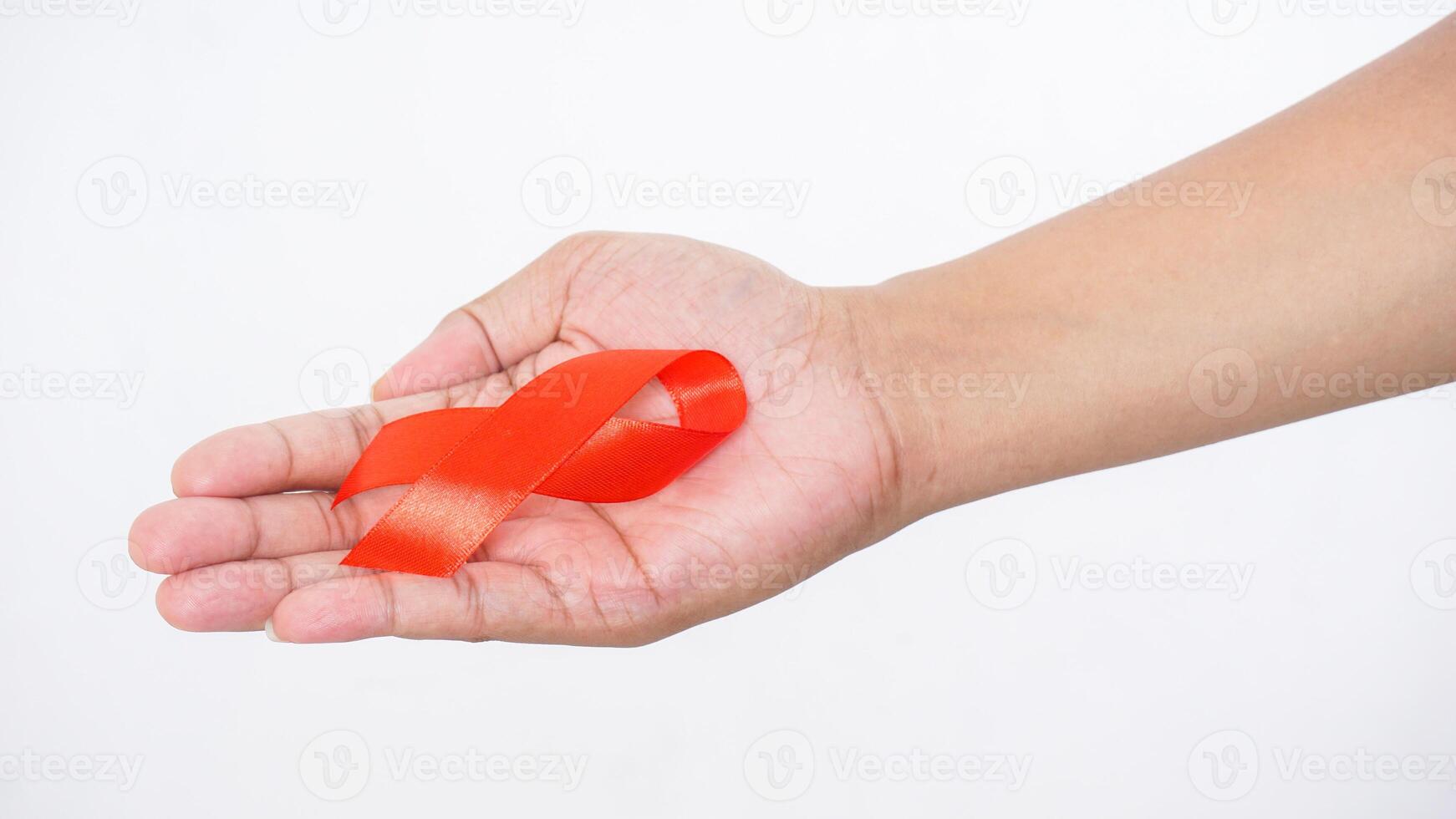 Red ribbon as HIV AIDS awareness symbol in man hands isolated on white background photo