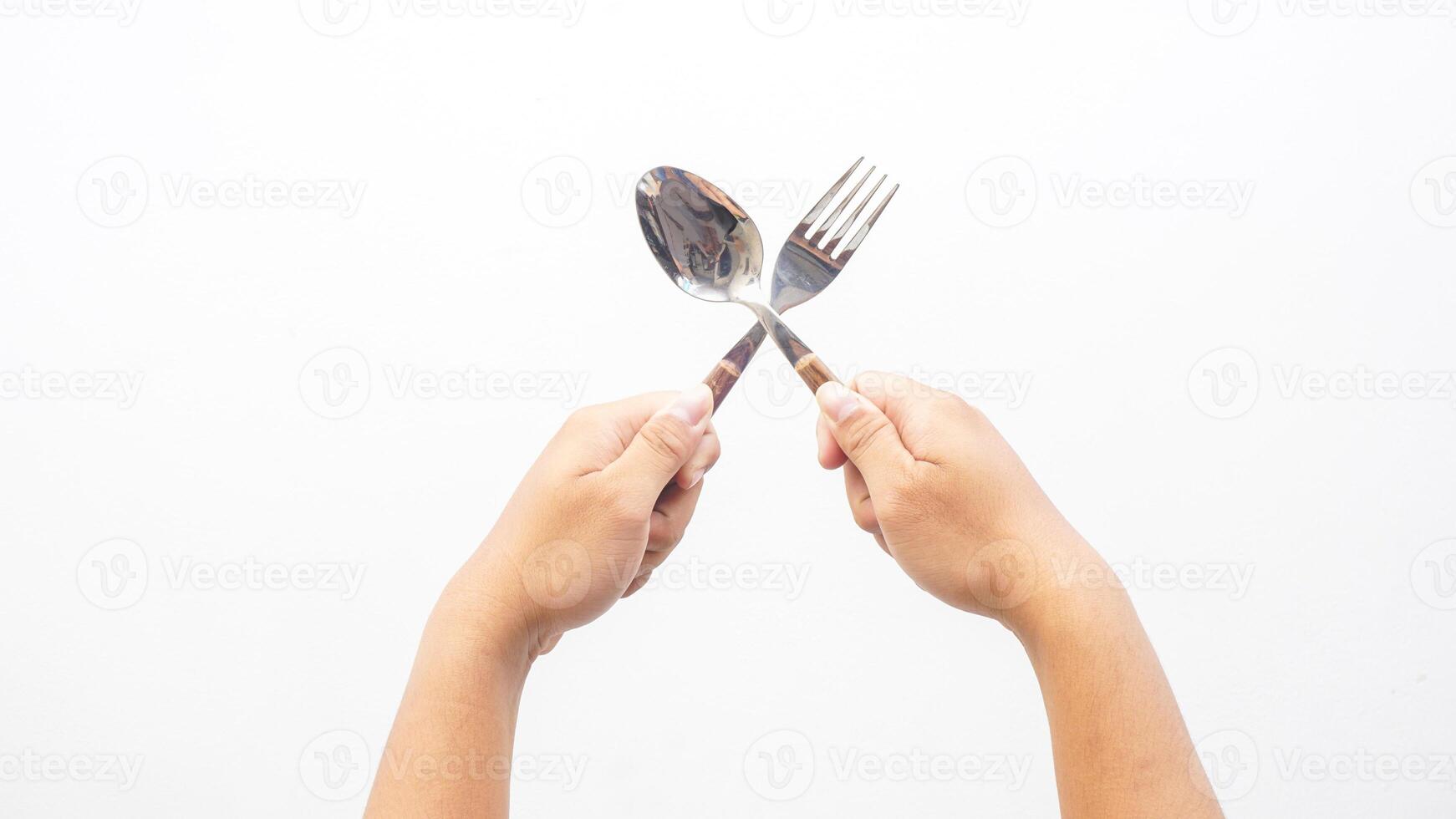 Hands Holding Stainless Steel Spoon and Fork with Wooden Handle Isolated on White Background photo