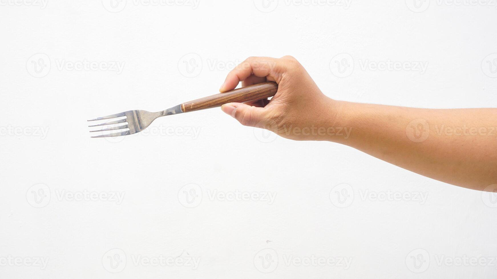 Hand of Man Holding Stainless Steel Fork with Wooden Handle Isolated on White Background photo