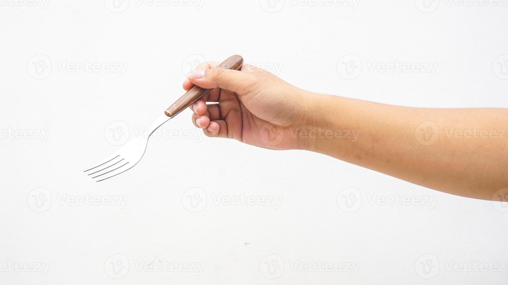 Hand Holding a Silver Stainless Fork with Wooden Handle Isolated on White Background photo