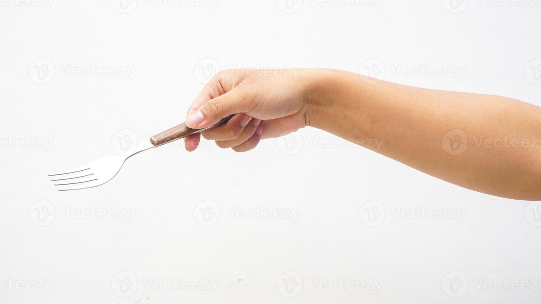 Hand of Man Holding a Silver Stainless Fork with Wooden Handle Isolated on White Background photo