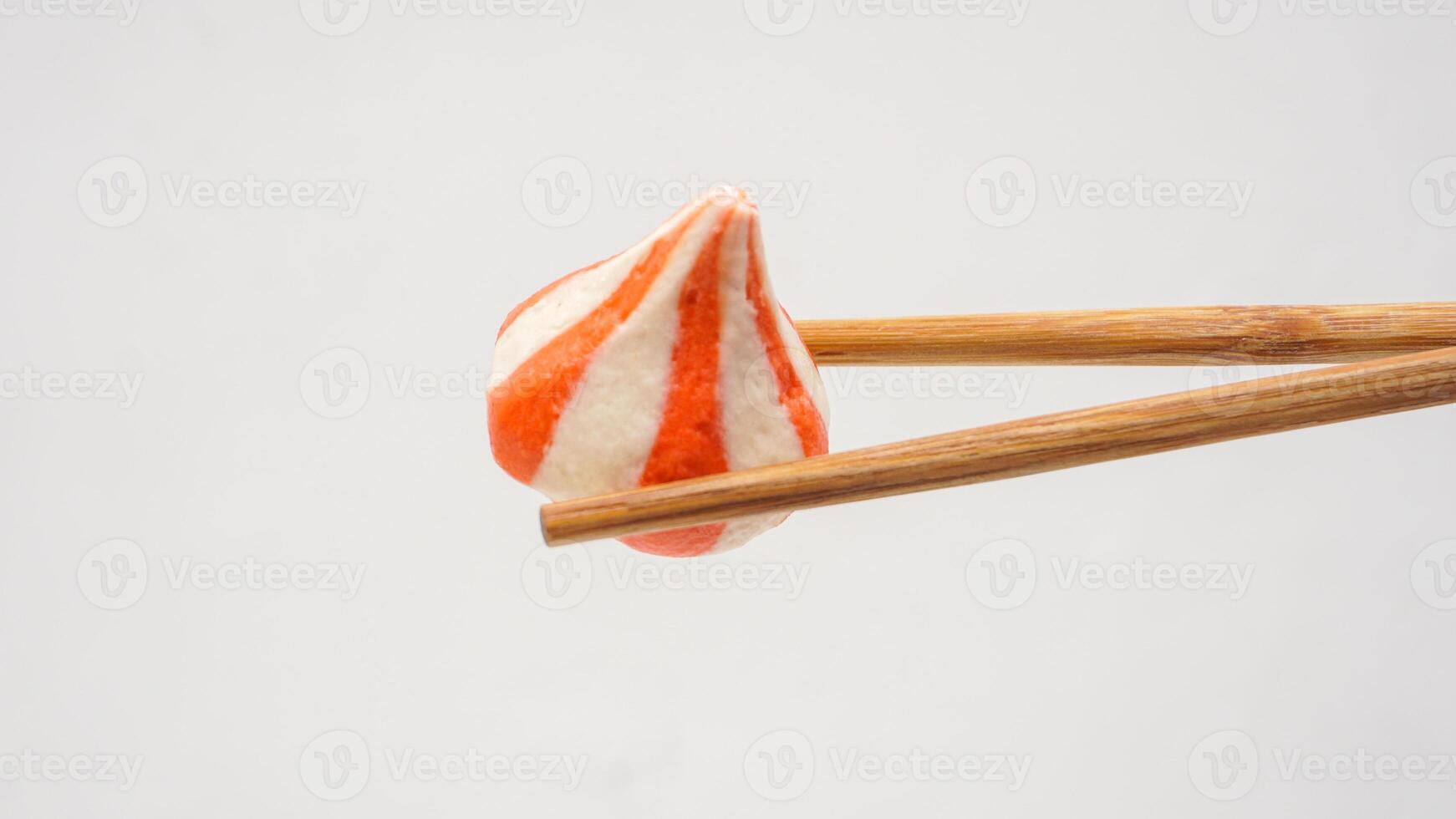 Wooden chopsticks holding fish dumpling balls stuffed with chicken meat isolated on white background photo
