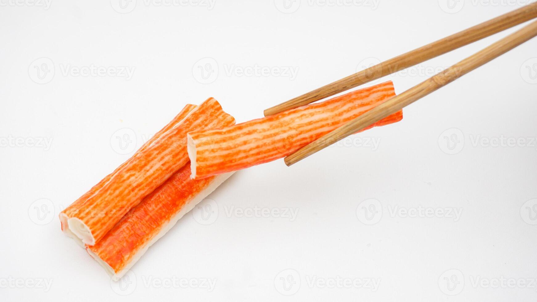 Crab stick or imitation crab meat made from processed fish meat picked up using chopsticks isolated on white background photo