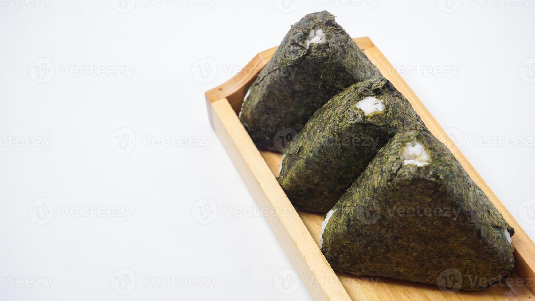 Three delicious onigiri or Japanese savory rice ball wrapped in nori dried seaweed on wooden coaster isolated on white background photo