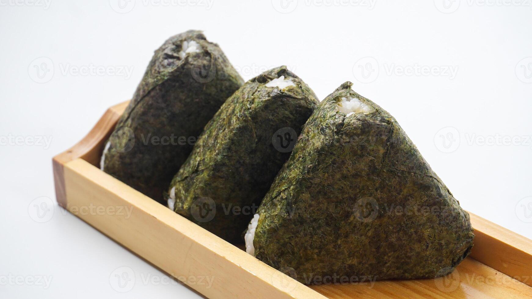 Three delicious onigiri or Japanese rice ball wrapped in nori dried seaweed on wooden coaster isolated on white background photo