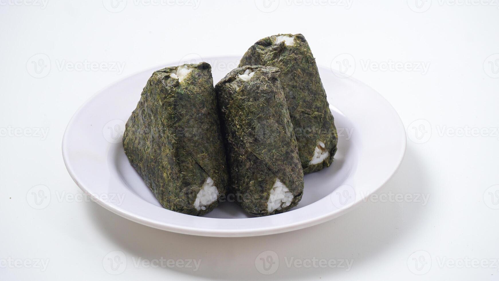 Three onigiri or Japanese rice ball in triangle shaped wrapped with nori or dried seaweed on plate isolated on white background photo