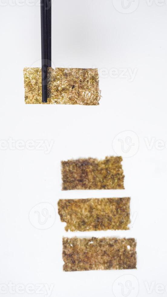 Chopsticks Picking Up Nori Seaweed Isolated on White Background photo