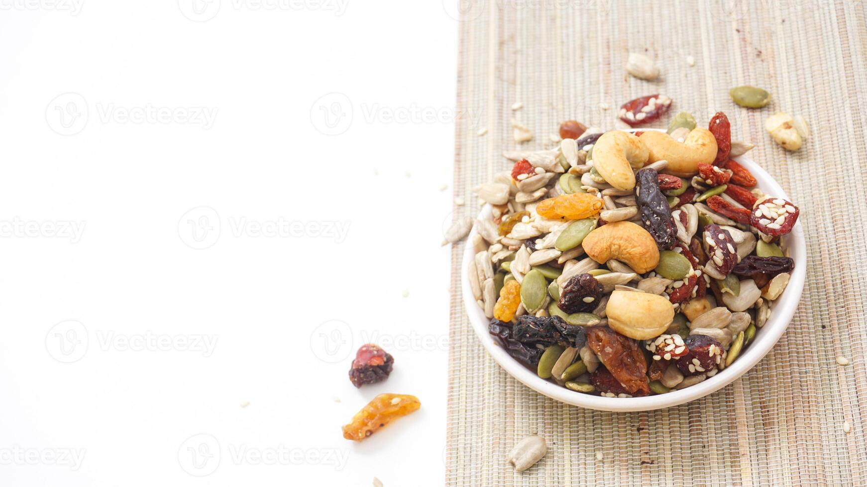Premium mixed nuts seeds and dried fruits on bowl isolated on white background photo