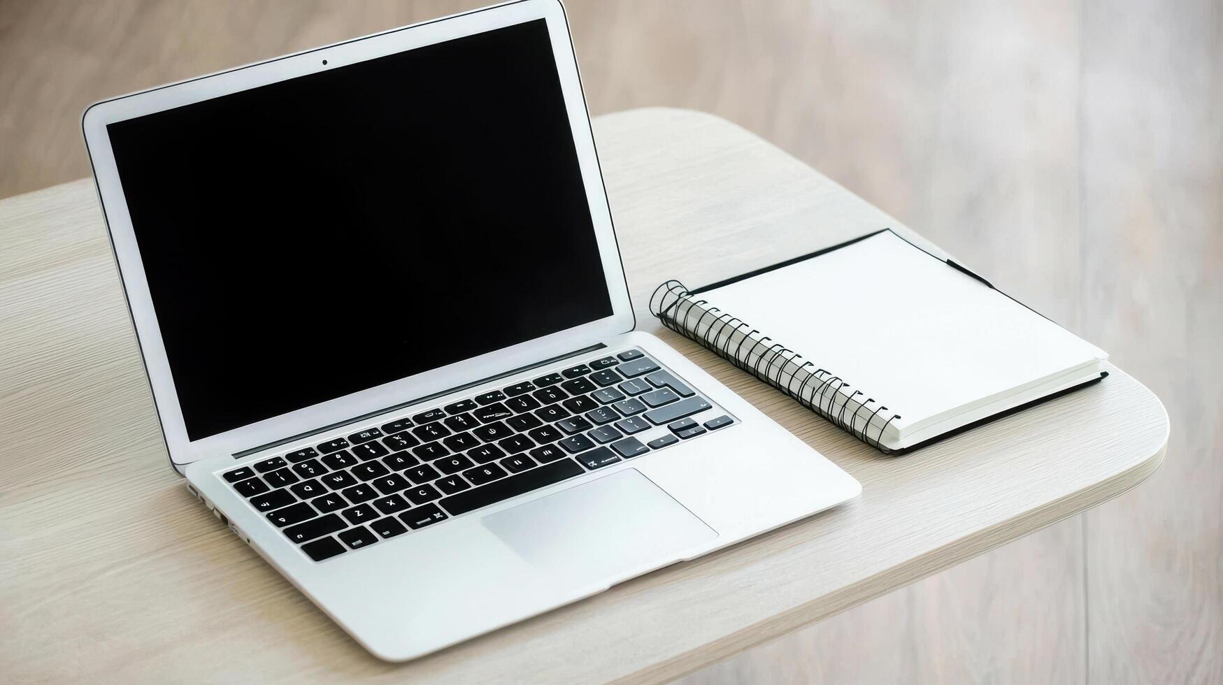 Minimalist workspace with laptop and open notebook on wooden table photo