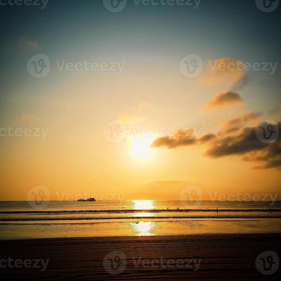 A person is standing on the beach at sunset photo