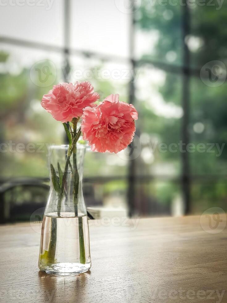 A vase with pink carnations sitting on a table photo