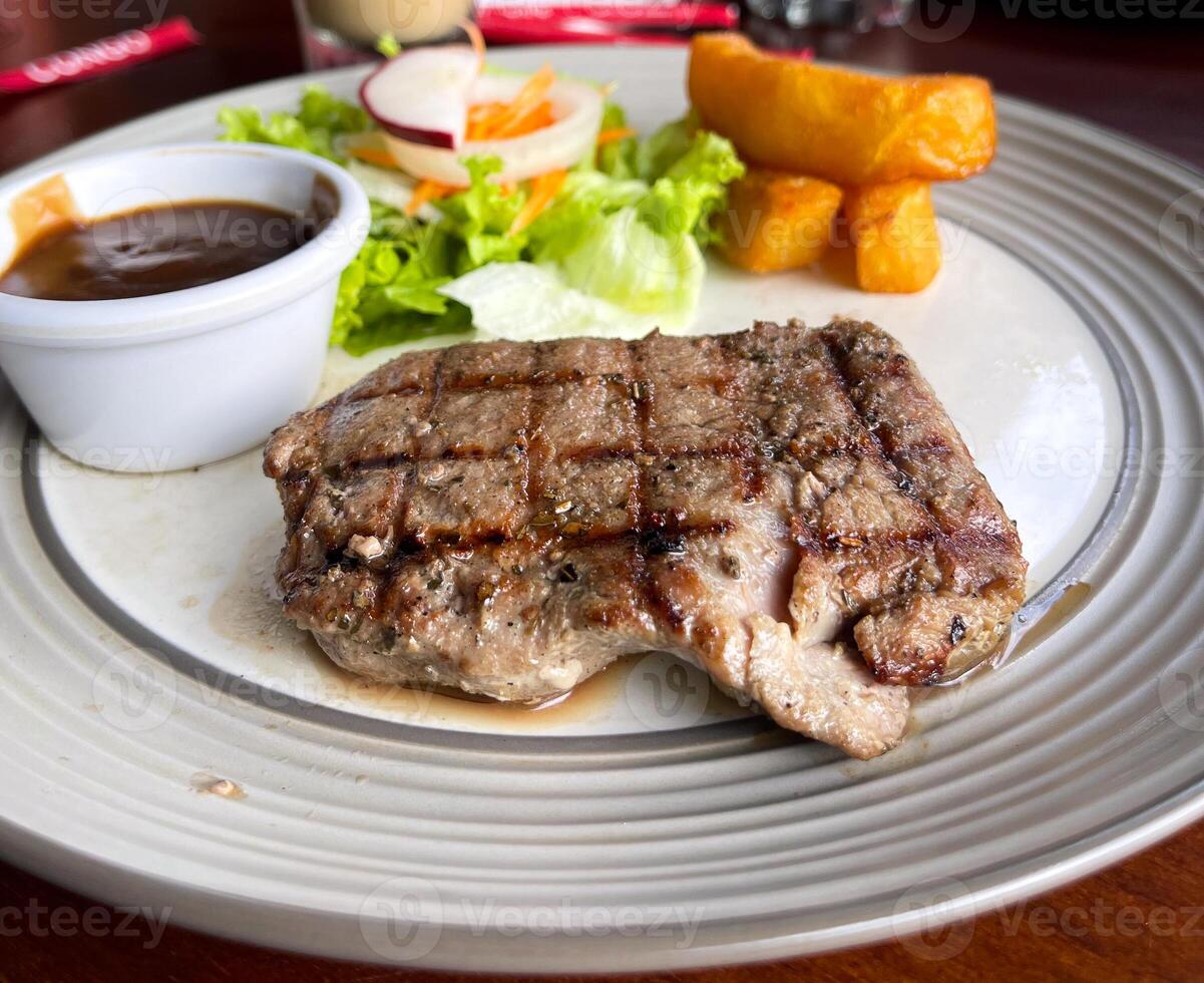 A plate of food with a side of salad and a side of sauce photo