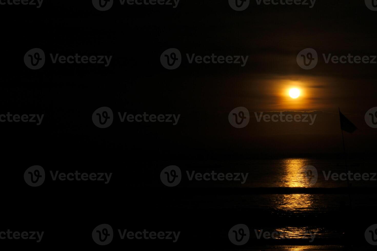 A full moon rising over the ocean photo