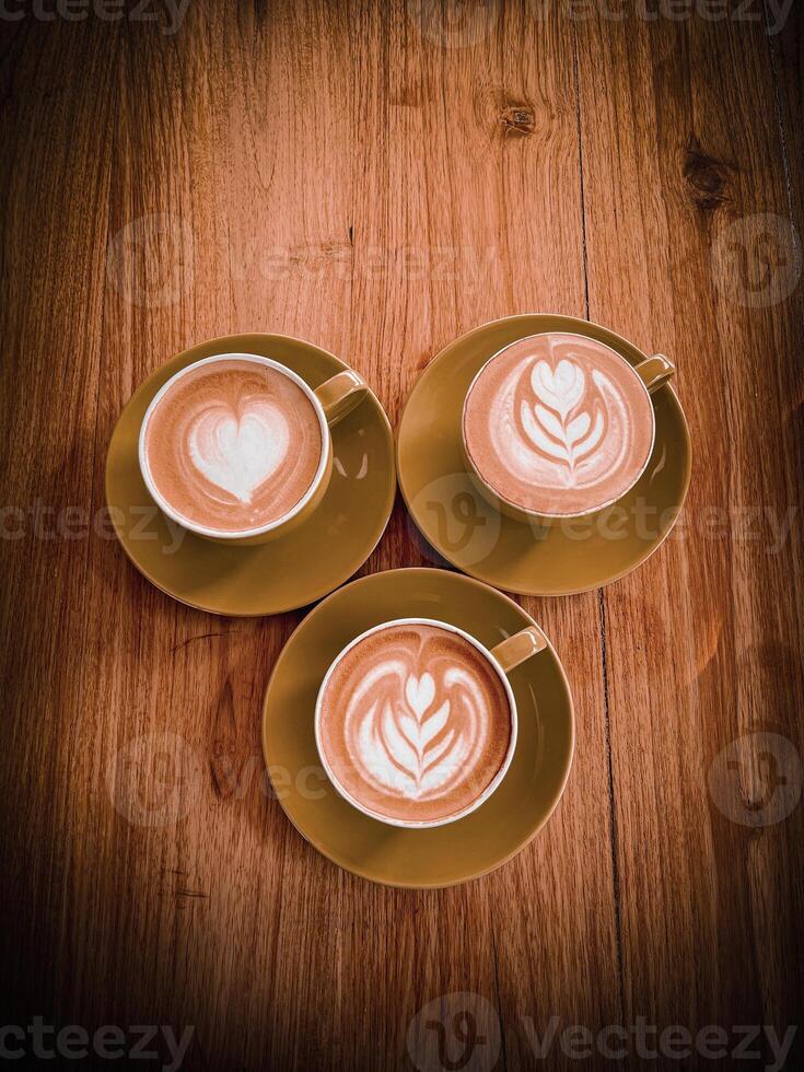 Three cups of coffee with latte art on wooden table photo