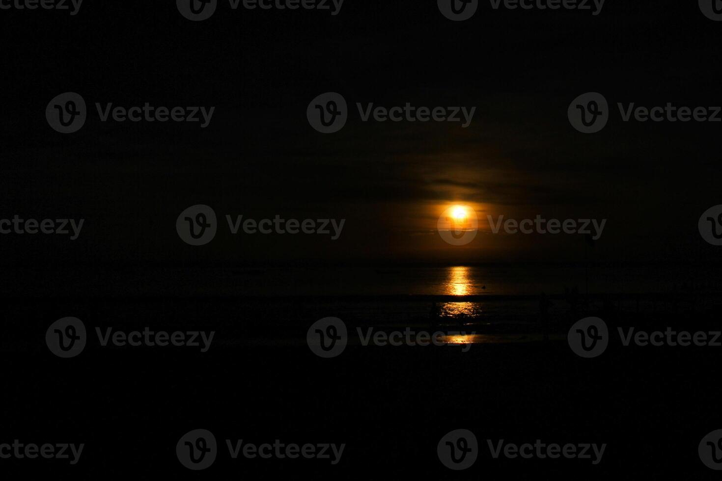 The moon is shining brightly over the ocean photo